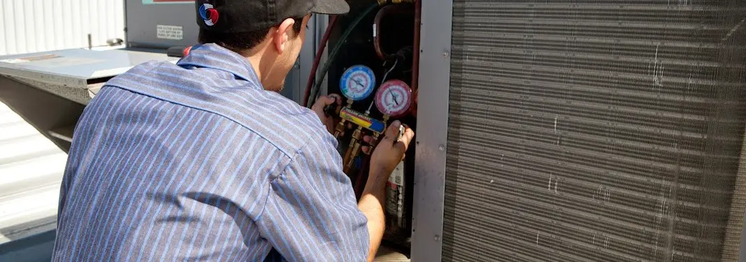 HVAC technician servicing a condenser unit in Maywood